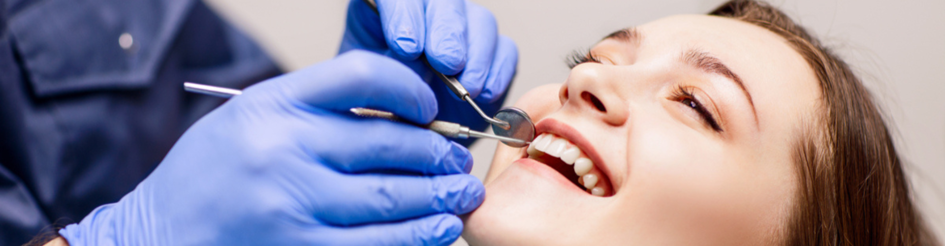 A dentist wearing blue gloves working on a patient.